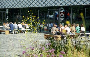 Exterior view of a modern office building at Science Park 301, Amsterdam East, featuring people networking outside. Ideal location for office space rental with ample community interaction opportunities.