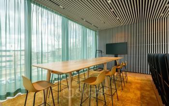 Modern conference room at Science Park 301, Amsterdam East, featuring a long wooden table, sleek high chairs, and a large screen, perfect for office space rental.