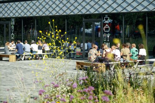 Exterior view of a modern office building at Science Park 301, Amsterdam East, featuring people networking outside. Ideal location for office space rental with ample community interaction opportunities.