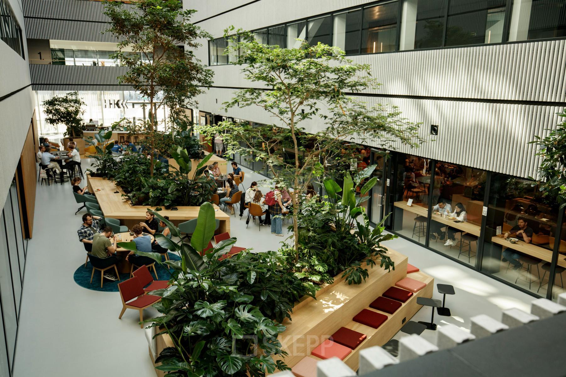 Modern interior at Science Park 301, Amsterdam East, featuring lush greenery and collaborative workspaces. Ideal for office space rental, the environment promotes creativity and productivity with open-plan seating and natural light.