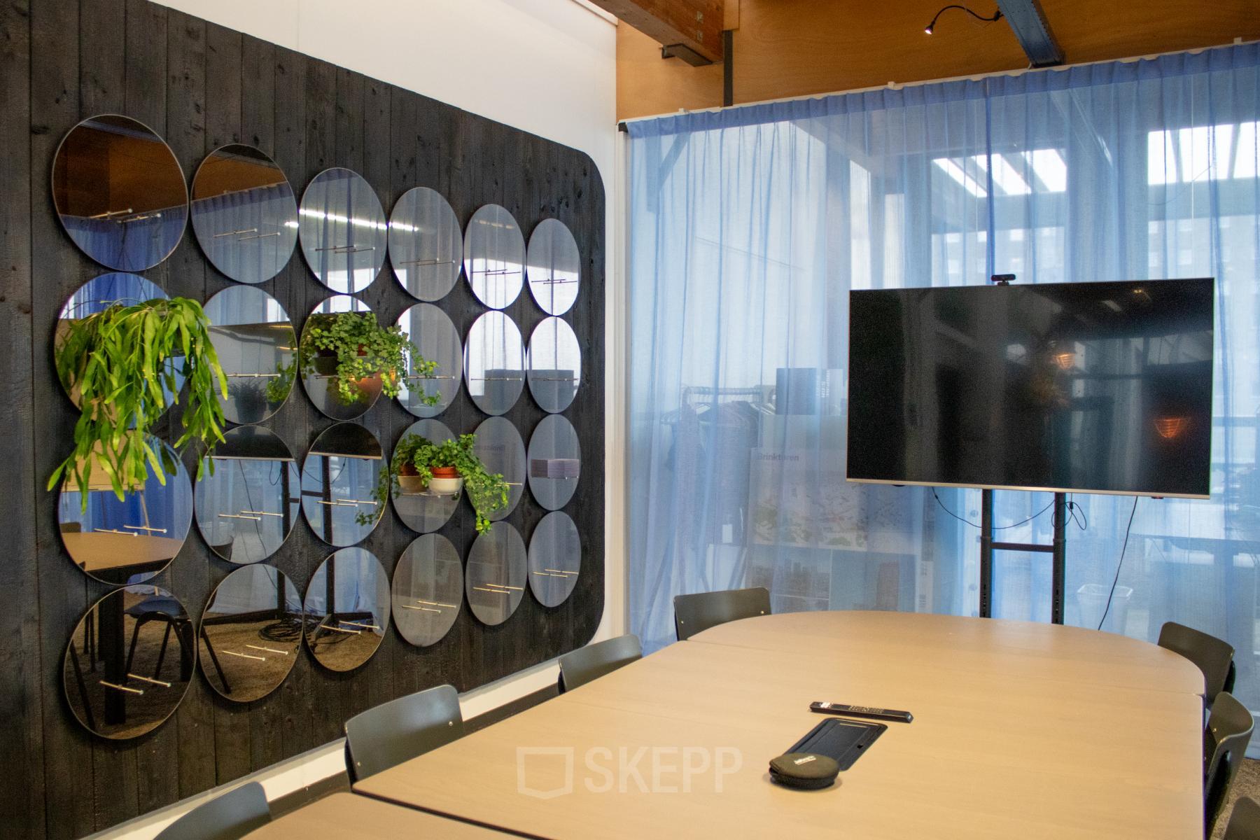 Modern office to rent at KNSM-Laan 171, Amsterdam East, featuring a meeting room with a large table, chairs, decorative plants, and a wall-mounted screen.