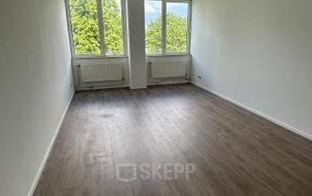 Empty office space at James Wattstraat 71, Amsterdam East, featuring large windows providing natural light and wooden flooring, ideal for office space rental.