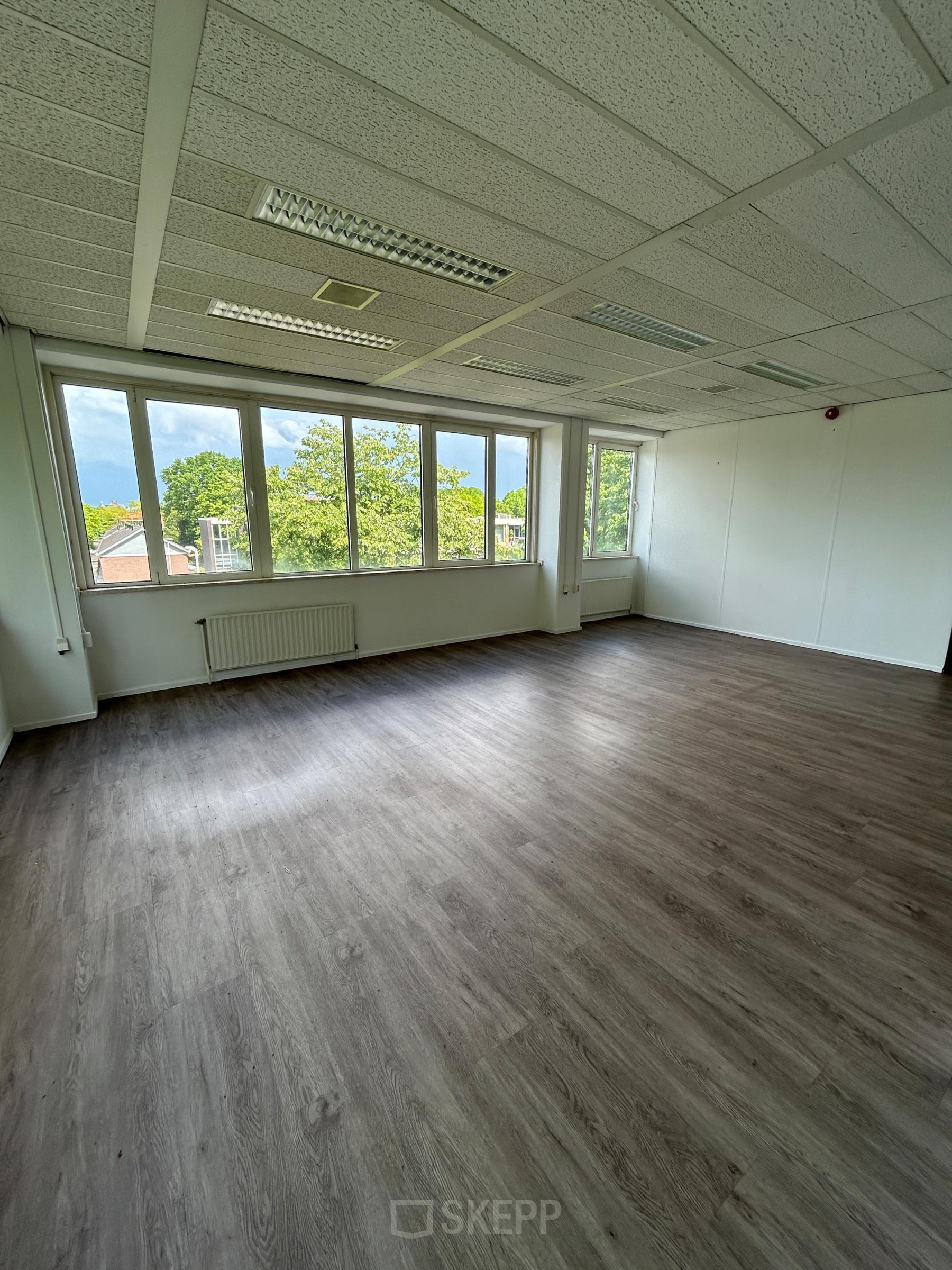 Unfurnished office space with large windows overlooking a green view at James Wattstraat 71, offering bright natural light, ideal for rent office space in Amsterdam East.