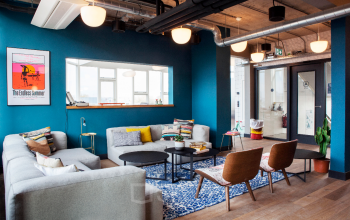 Modern lounge area at Weesperstraat 61, Amsterdam East, featuring cozy seating, colorful decor, and industrial-style design with office space rental options.