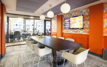 Colorful conference room at Weesperstraat 61, Amsterdam East, featuring a large table, modern chairs, and vibrant decor. Office space rental available.