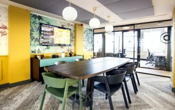 Bright office space rental at Weesperstraat 61, Amsterdam East, featuring a modern conference room with a long table, chairs, and vibrant decor.