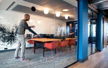 Modern office interior at Weesperstraat 61, Amsterdam East, featuring a conference room with vibrant decor and two people playing ping pong.