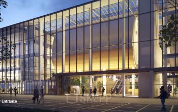 Exterior view of the modern office building located at Jacob Bontiusplaats 9, Amsterdam East, Amsterdam, featuring a glass facade and illuminated interior spaces with people approaching the entrance.