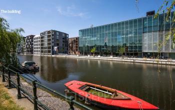 Modern office building at Jacob Bontiusplaats 9, Amsterdam Oost, with canal and moored boats on a sunny day, showcasing ideal office space rental location.
