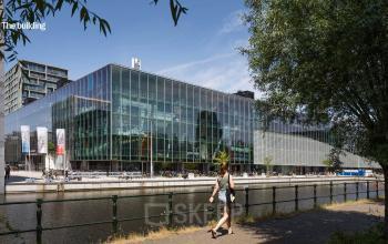 Modern glass office building at Jacob Bontiusplaats 9 in Amsterdam East, reflecting the surrounding trees and water, ideal for office space rental.