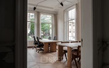 Furnished office space to rent on Jacob Obrechtstraat 56 in Amsterdam Old South, featuring wooden tables and chairs with large windows letting in natural light.