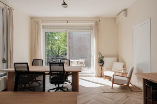 Bright office space rental in Amsterdam Old South with wooden desks, chairs, and a balcony view, located at Jacob Obrechtstraat 56.