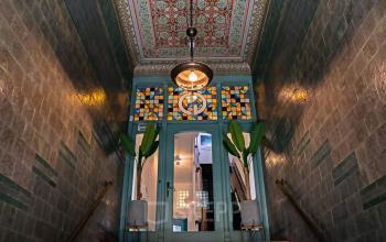 Entrance area at Emmalaan 7-9, Amsterdam Old South, showcasing decorative tiles and stained glass, perfect for those looking to rent office space.