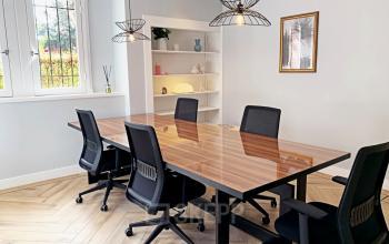 Bright office space rental in Amsterdam Old South with a wooden table and four chairs, under modern pendant lights. Ideal environment for meetings or collaborative work. Available for rent at Emmalaan 7-9.