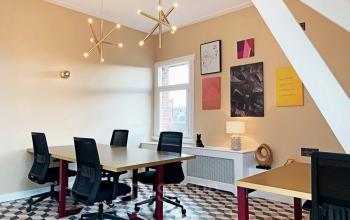 Bright office space rental with modern lighting, geometric flooring, and contemporary art on the walls, available in Amsterdam Old South at Emmalaan 7-9.
