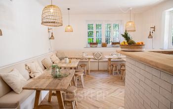 A cozy office to rent in Amsterdam Old South with wooden tables, cushioned benches, and natural light through large windows, perfect for work or meetings. Ideal for office space rental.