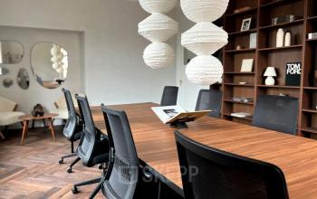 Office space with a long wooden table, black chairs, pendant lights, and a bookshelf, available for rent at Emmalaan 7-9, Amsterdam Old South.