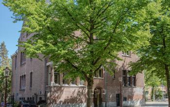Exterior view of Emmalaan 7-9, Amsterdam Old South showcasing the brick office building surrounded by lush green trees, ideal for office space rental.