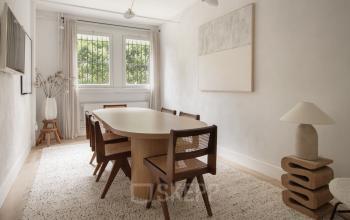 Bright office to rent in Amsterdam Old South, featuring a stylish table with chairs, modern lamp, and wall art, perfect for meetings or collaborative work.