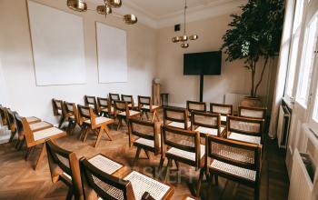 Light-filled conference room at Emmalaan 7-9 in Amsterdam Old South, featuring neatly arranged wooden chairs and a large screen. Ideal for office space rental.