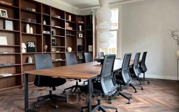 Furnished office space at Emmalaan 7-9, Amsterdam Old South, featuring a meeting table with chairs and wooden shelving in the background, ideal for office space rental.