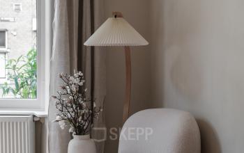 A cozy corner in an Amsterdam Old South office, featuring a plush chair and a side table by a window.