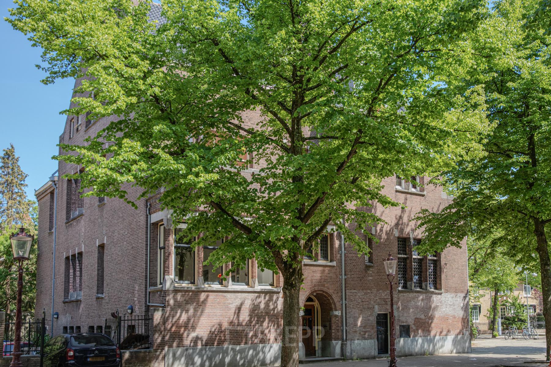 Exterior view of Emmalaan 7-9, Amsterdam Old South showcasing the brick office building surrounded by lush green trees, ideal for office space rental.