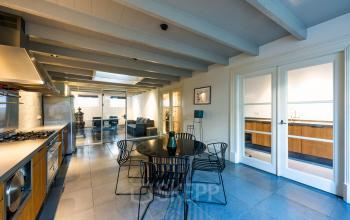 Modern office space with sleek furnishings in Amsterdam Old South, featuring a round table, stylish chairs, and an elegant kitchen area, ideal for office space rental.
