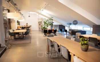 Modern office space rental at Olympisch Stadion 24-28, Amsterdam Old South, featuring an open floorplan with multiple workstations, contemporary decor, and ample lighting.
