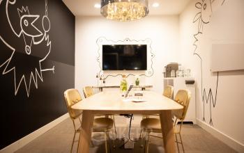 Conference room at Olympisch Stadion 24-28, Amsterdam Old South, featuring a large wooden table, gold chairs, modern decor, and a wall-mounted screen.