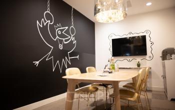 Modern conference room with a wooden table, gold chairs, a wall-mounted TV, and unique black wall art at Olympisch Stadion 24-28, Amsterdam Old South.