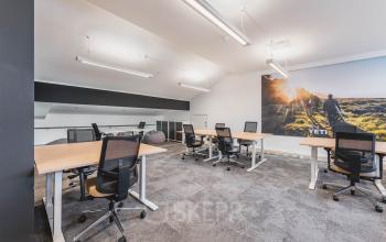 Modern office space with multiple desks and chairs, located in Olympisch Stadion, Amsterdam Old South, available for rent. Large wall art and ample lighting enhance the professional environment.