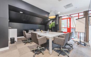 Modern office space rental in Amsterdam Old South featuring a conference room with a long table, ergonomic chairs, and bright natural lighting at Olympisch Stadion 24-28.