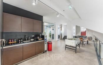 Modern office space rental in Amsterdam Old South featuring a sleek kitchenette and spacious recreational area with a foosball table at Olympisch Stadion 24-28.