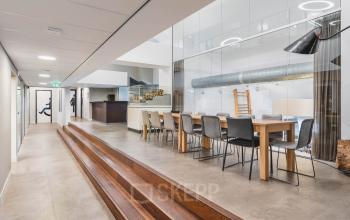 Spacious modern office with long meeting table and seating, featuring sleek design and ample lighting at Olympisch Stadion 24-28, perfect for office space rental in Amsterdam Old South.