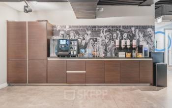 Office pantry at Olympisch Stadion 24-28 in Amsterdam Old South, featuring modern cabinetry, coffee machine, and beverage dispensers, ideal for your next office space rental.