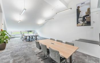 Modern office space at Olympisch Stadion 24-28 features a well-lit, open workspace with a conference table and a seating area near a window. Ideal for those seeking office space rental in Amsterdam Old South.