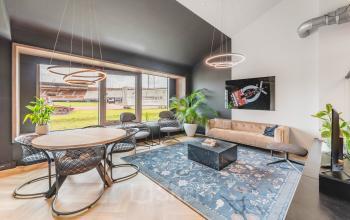 Stylish office lounge at Olympisch Stadion 24-28, Amsterdam Old South, featuring modern furniture, a rug, and large windows. Ideal office space rental.