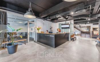 Reception area of an office space available for rent at Olympisch Stadion 24-28, Amsterdam Old South, featuring a welcoming desk, potted plants, and modern furnishings.
