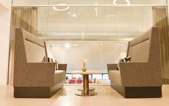 Modern furnished lounge area with two grey sofas and a small round table at Olympisch Stadion 24-28, Amsterdam Old South, available for office space rental.