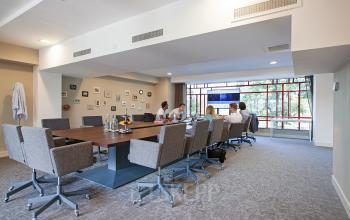 Conference room in office space located at Olympisch Stadion 24-28, Amsterdam Old South, Amsterdam, with people seated at a long table engaged in a meeting, modern furnishings, and large windows.
