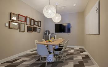 Meeting room with a wooden table, six chairs, wall-mounted TV, whiteboard, decorative mirrors, modern lighting, and geometric patterned carpet at Olympisch Stadion 24-28, Amsterdam Old South.