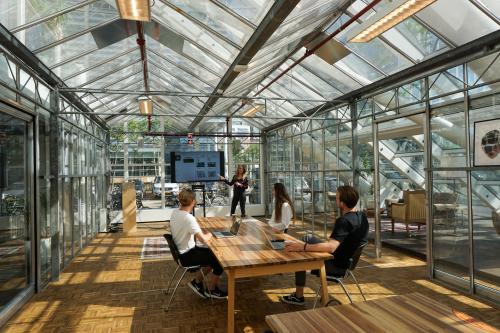 Bright and modern workspace at Johan Huizingalaan 400, Amsterdam Riekerpolder, featuring glass walls, wooden desks, and people engaged in a meeting. Ideal for office space rental with a dynamic and open atmosphere.