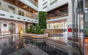 A modern office space rental featuring a sleek reception area with polished floors and lush greenery at John M. Keynesplein 4-10, Amsterdam Riekerpolder.