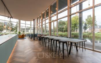 Bright and open workspace with large windows and modern furnishings, offering office space rental at John M. Keynesplein 4-10, Amsterdam Riekerpolder.