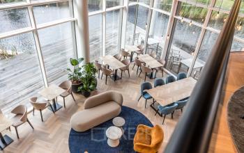 Spacious, modern office space with stylish furniture and large windows overlooking a water view, ideal for office space rental.