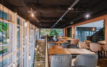 A stylishly furnished workspace at John M. Keynesplein, featuring contemporary seating and hanging lights, ideal for office space rental in Amsterdam Riekerpolder.