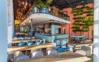 Modern, vibrant office space in Amsterdam Riekerpolder featuring lush vertical gardens, a playful foosball table, and ample natural light. Ideal for rent office space with furnished workspaces and communal areas.