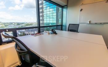 Furnished office space with a large window view at Radarweg 29, Amsterdam Sloterdijk, showcasing a table, chairs, and a whiteboard, perfect for rental.