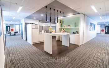 A modern office space at Radarweg 29, Amsterdam Sloterdijk, featuring a furnished area with a central high table and decorative shelves, ideal for office space rental.